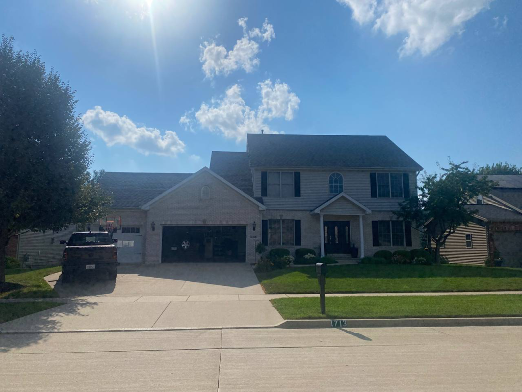 Homeowner documenting storm damage for a roof insurance claim in Illinois with an inspector on the roof
